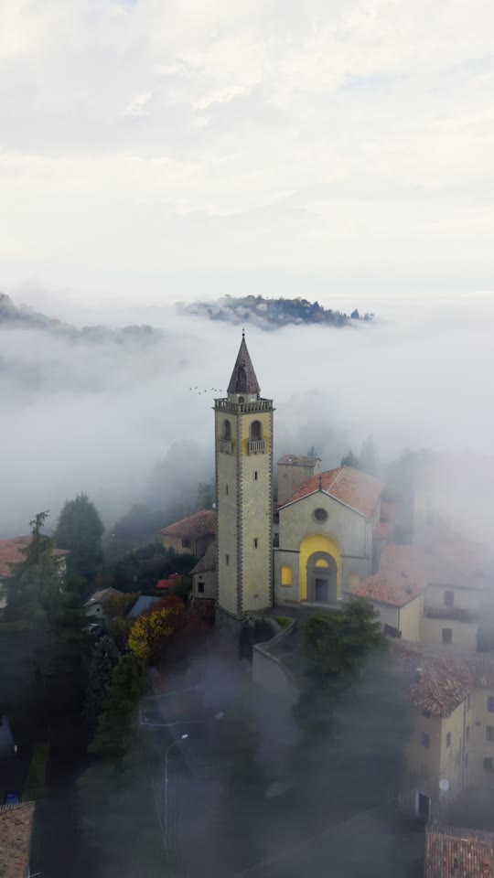 Riprese drone di un campanile che emerge dalla nebbia