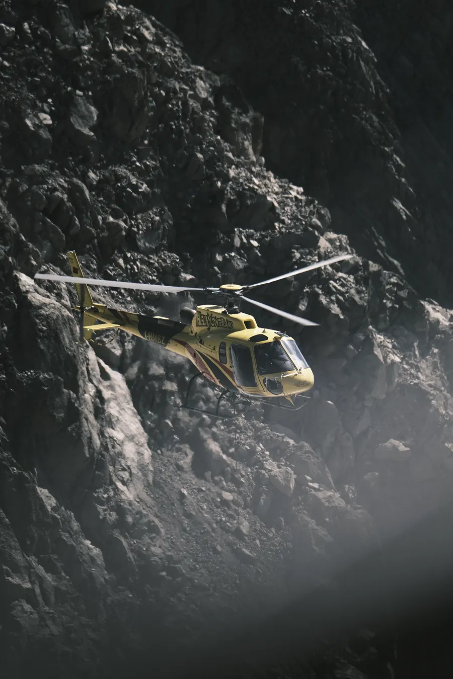 Elicottero giallo in volo vicino a una parete di roccia