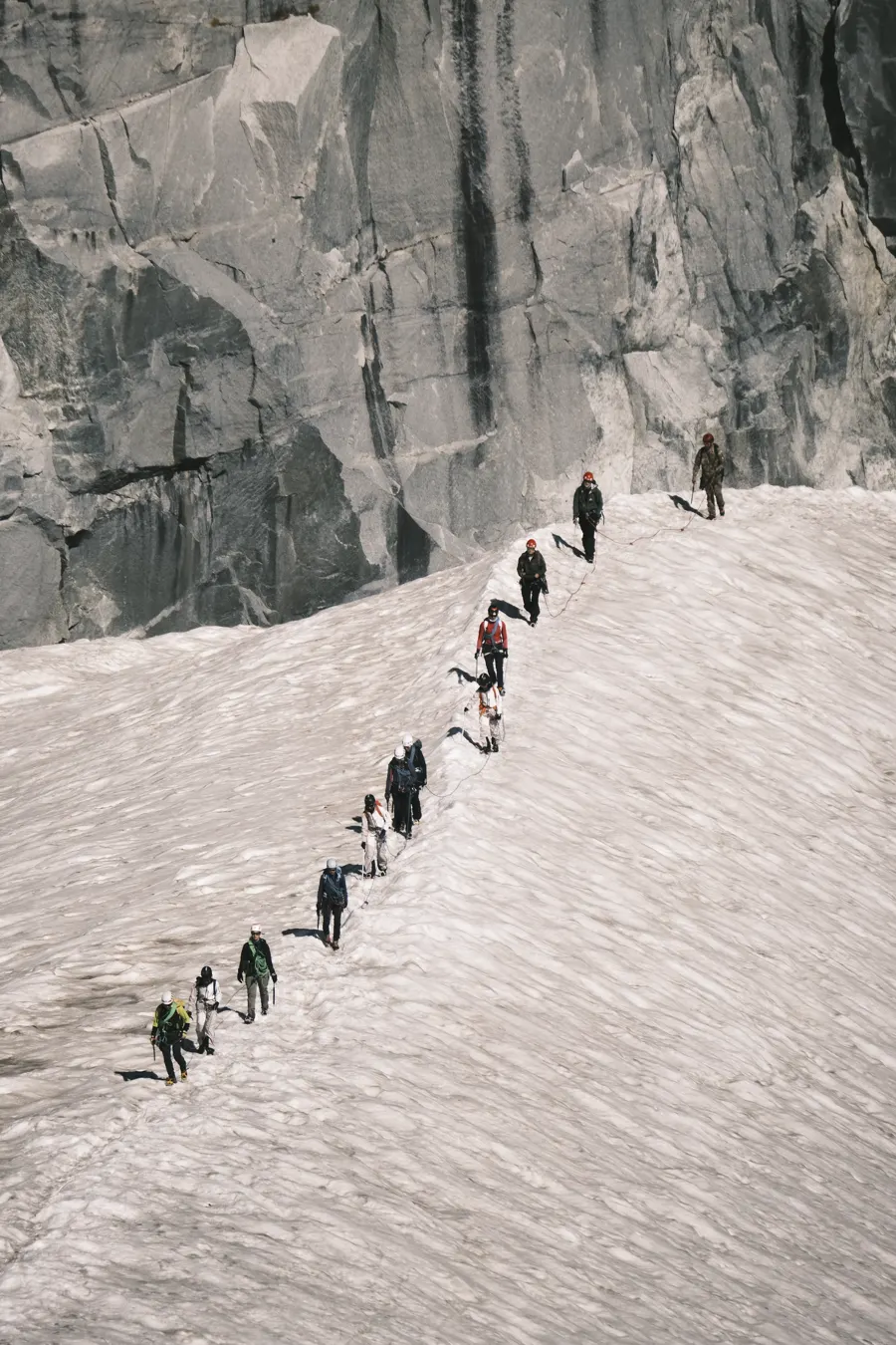 Fila di escursionisti che salgono un pendio innevato
